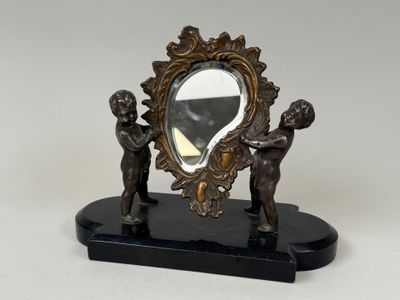 une statue représentant deux enfants, avec un miroir posé sur une table