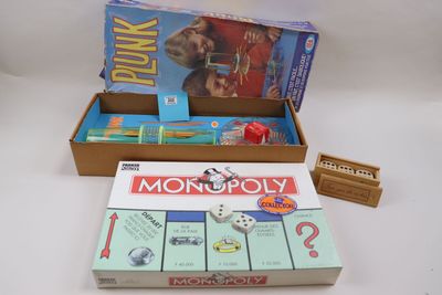 un jeu de société « Monopoly » dans une boîte, avec une boîte de cartes à côté