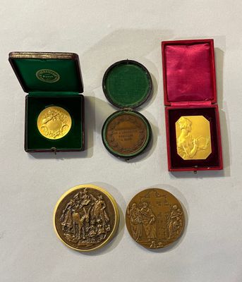 trois médailles d'or et d'argent dans un coffret rouge posé sur un fond blanc