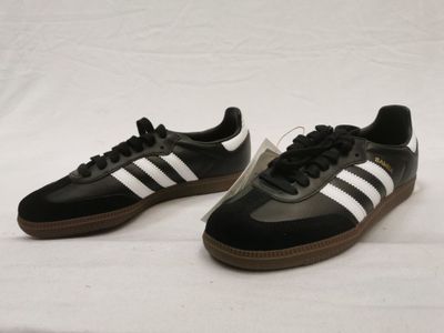 une paire de baskets Adidas noires et blanches sur fond blanc