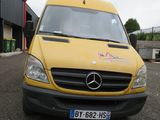 une camionnette jaune garée sur un parking à côté d'un immeuble