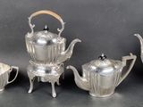a silver tea set on a table next to other silver items