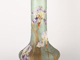 un vase vert orné de fleurs violettes sur fond blanc