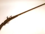 un vieux fusil avec une poignée en bois sur une surface blanche