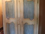 a white armoire with blue glass doors in the corner of a room