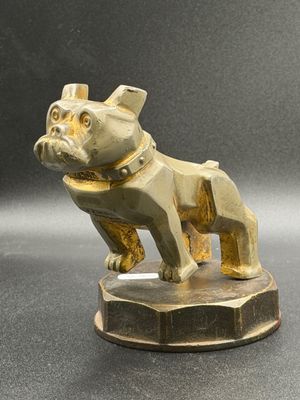 brass figurine of a dog on a pedestal on a gray surface