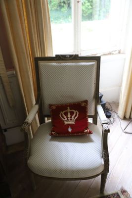 une chaise blanche sur laquelle est posé un coussin rouge