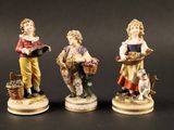trois figurines représentant des enfants avec des paniers de fleurs et un chien