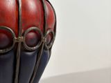 a red and blue vase that has tomatoes on top of it