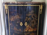 a black cabinet with a painting on it and a bowl on top of it