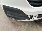 the front bumper of a white car with a hole in it