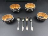 four silver spoons and four silver bowls with spoons on a table