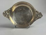 un plateau d'argent antique sur un support sur une surface blanche