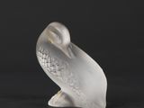 a white figurine of a bird sitting on a black surface