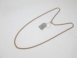 une chaîne en or à laquelle est accrochée une médaille, posée sur une surface blanche