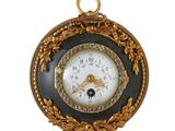 une horloge dorée et noire accrochée à un mur blanc