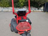 a red lawn mower parked in a parking lot