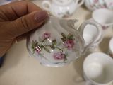 a person holding a tea pot and cups on a table
