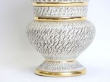 a white and gold vase with a lid on a white background