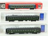trois wagons de train miniature sont exposés dans une vitrine posée sur une surface blanche