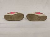 pair of children ' s pink and brown shoes on a white surface