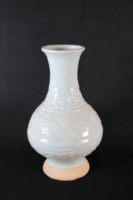 a white vase that is sitting on a wooden stand