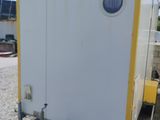 une photo représentant des toilettes portables blanches et jaunes dans un parking