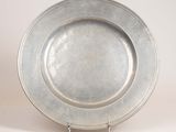 a silver plate on a metal stand on a white surface