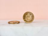 a gold coin sitting on top of a marble slab next to a gold coin