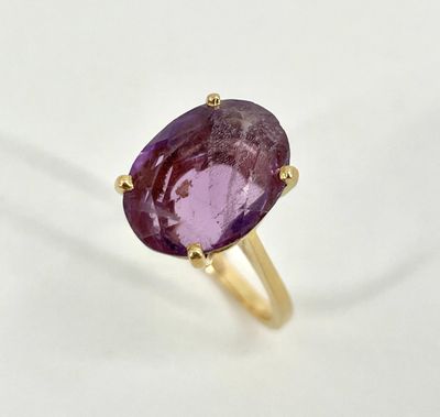 a close up of a purple stone ring on a white surface