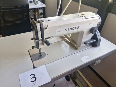 une machine à coudre blanche posée sur une table dans une pièce