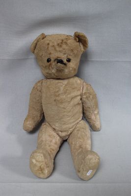 a brown teddy bear that is sitting on a white sheet