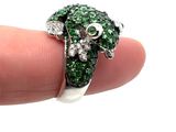 a person holding a ring with green and white stones on it