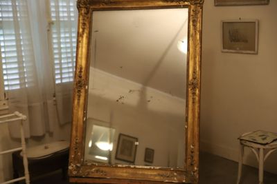un grand miroir dans un coin de la pièce, à côté d'un fauteuil
