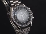 un gros plan d'une montre montée sur un bracelet en métal, sur fond noir