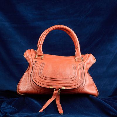 un sac à main en cuir orange sur fond bleu