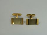 a pair of gold cufflinks on a white surface