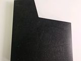 a close up of a piece of black paper on a white surface