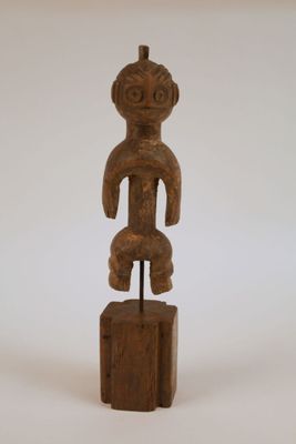 une image représentant une statue en bois d'un homme posée sur un bloc de bois