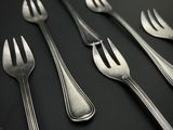 cinq fourchettes et deux cuillères sur une table noire