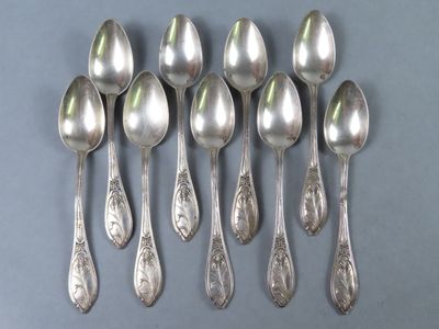 six cuillères en argent sont alignées sur une surface grise