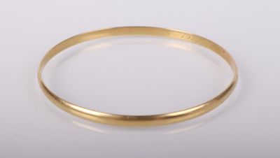 gros plan d'un bracelet en or sur une surface blanche