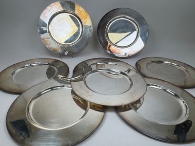 six assiettes en métal argenté sont disposées en cercle sur une table