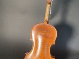 an old violin sits on a stand against a gray background