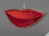 an ornament with a red lip hanging from a tree