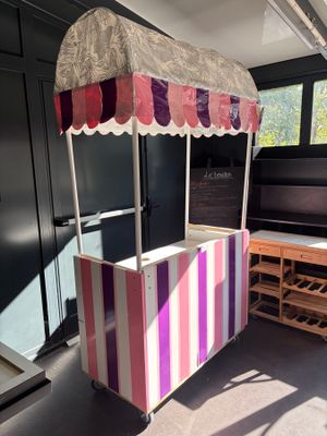 a pink and white striped food cart in the middle of a room
