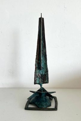 sculpture en bronze représentant un cône posé sur un socle, sur une surface blanche