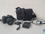 a camera, a camera bag, and other electronics laid out on a table