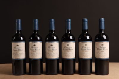 six bouteilles de vin rouge sont alignées sur une table