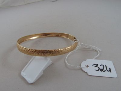 a gold bracelet and a tag on a white table